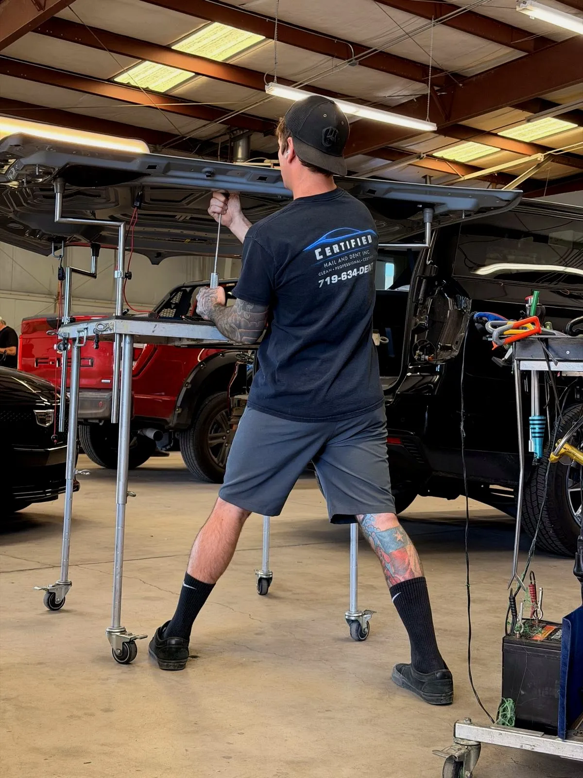 Technician repairing hail dents on a body panel in Colorado Springs